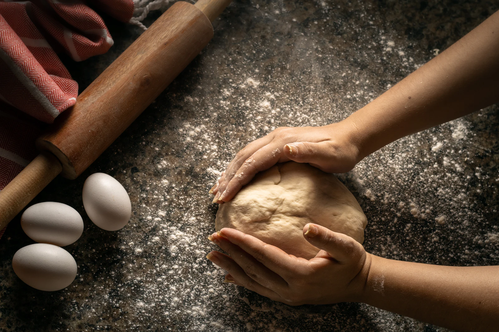 Bemehlte Arbeitsfläche mit einem ausgerollten Mürbeteig, Teigrolle, Butterwürfeln und frischen Eiern